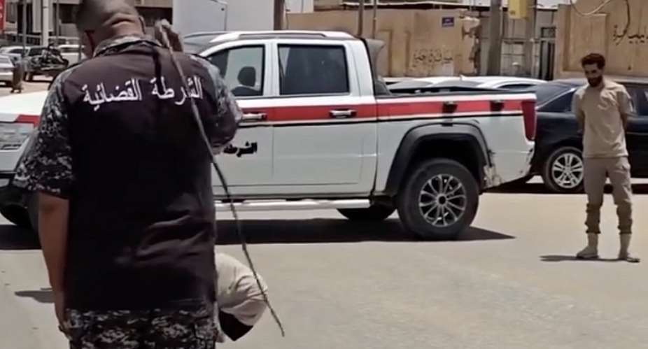 July 21st 2026, Sabha, Libya: a woman is sentenced to 100 lashes for adultery. She is seen kneeling on a mattress in the middle of a street blocked by a judicial police vehicle. One officer reads out the verdict, then another carries out the sentence.  Instagram / @feminists_of_libya -  Instagram / @feminists_of_libya