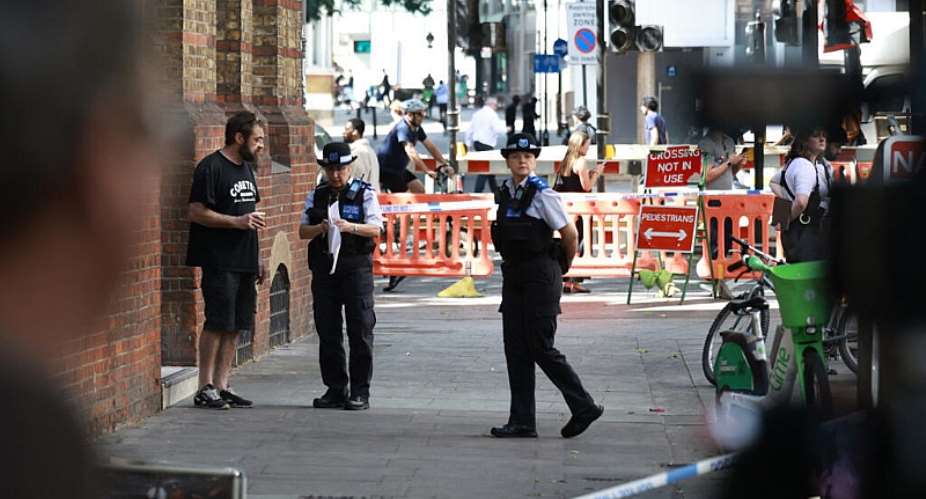 Police community support officers (PCSOs) stand behind cordon tape at Endell road in Covent Garden, central London on August 5, 2026. -  Henry Nicholls, AFP