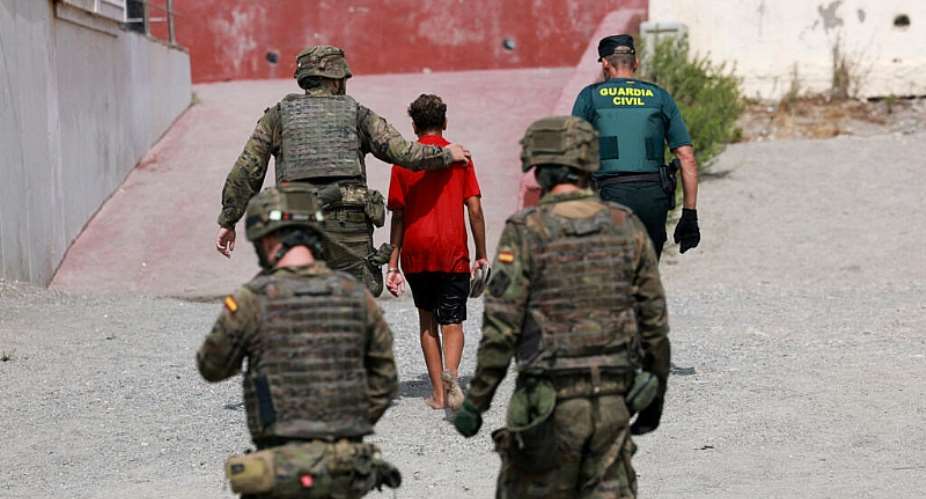 A minor from Morocco is escorted by Spanish security forces after attempting to cross into Ceuta by sea, 1 August. - REUTERS - Violeta Santos Moura