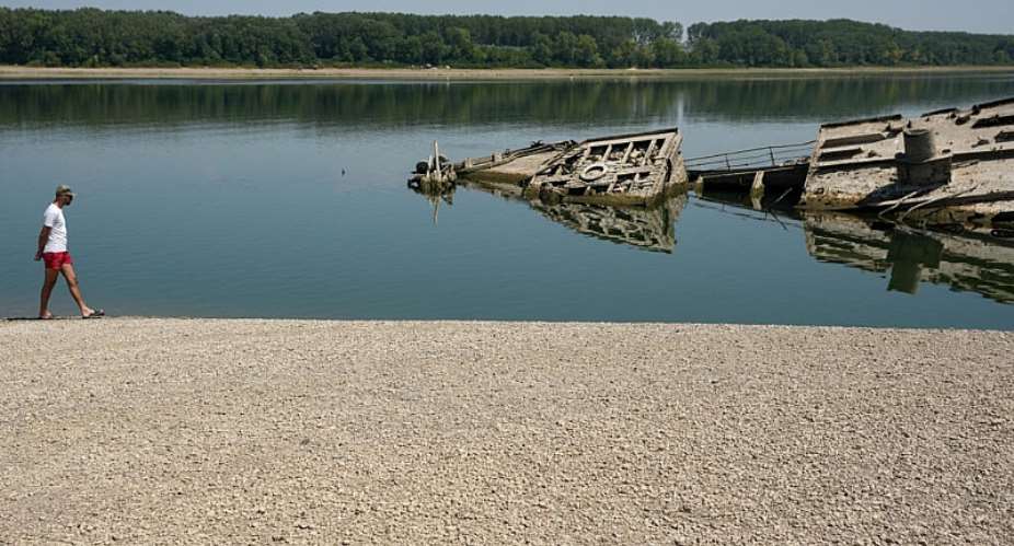 A man walks on a sandbank near wreckage of a German WWII warship which was exposed due to drought impacts on the Danube River in Serbia, August 4, 2026. -  Darko Vojinovic, AP