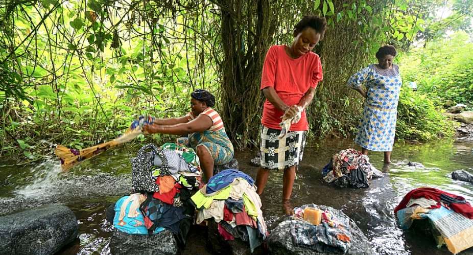 Women displaced from rural villages in the Anglophone region gather to wash clothes in a stream.  - Source: Photo by Giles ClarkeUNOCHA via Getty Images