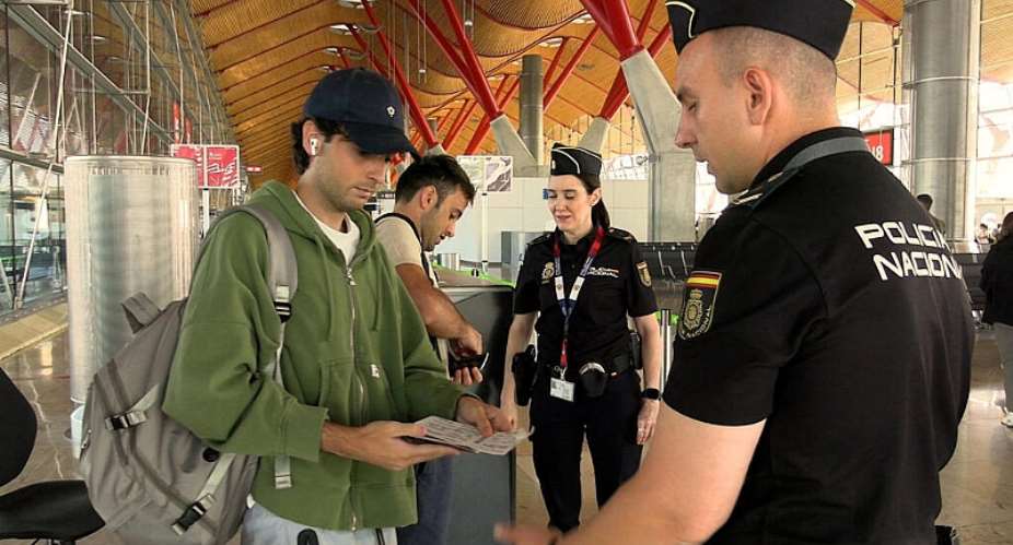 Spanish national police officers check the documents of travellers arriving from Italy, after Spains government said it would establish border controls for flights and ships from Italy, from midnight on Saturday until September 7, in a dispute over irregular migration, at Madrid-Barajas Airport in Madrid, Spain, August 8, 2026. -  Spanish police, via Reuters
