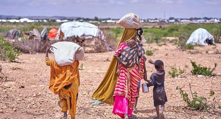 A Somali mother and her children displaced by flooding search for a place to take shelter among other families who have already found refuge on higher ground. Photo: IOM/ Ismail Abdihakim Ismail