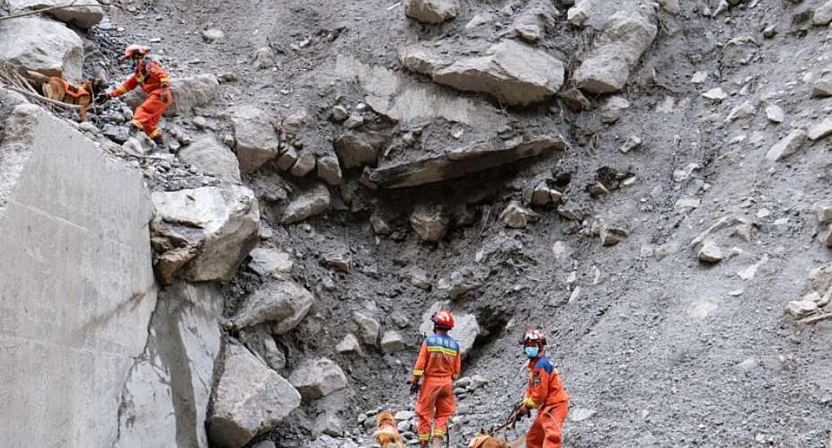 Fire and rescue personnel use dogs to search for victims of a mudslide beside the road which leads to Gyirong Port in Gyirong County, in China’s western Tibet region. -  AFP