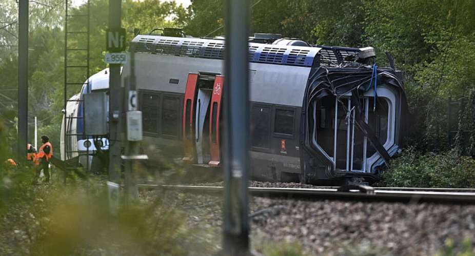 SNCF workers stand next to a derailed train carriage in Clon, northwestern France, on September 12, 2026, the morning after the train derailed. A total of 44 people were injured, including a woman who was evacuated as a top priority following September 11, 2026 evenings derailment of a TER train carrying 186 passengers between Rouen and Caen -  AFP/Guillaume Saligot