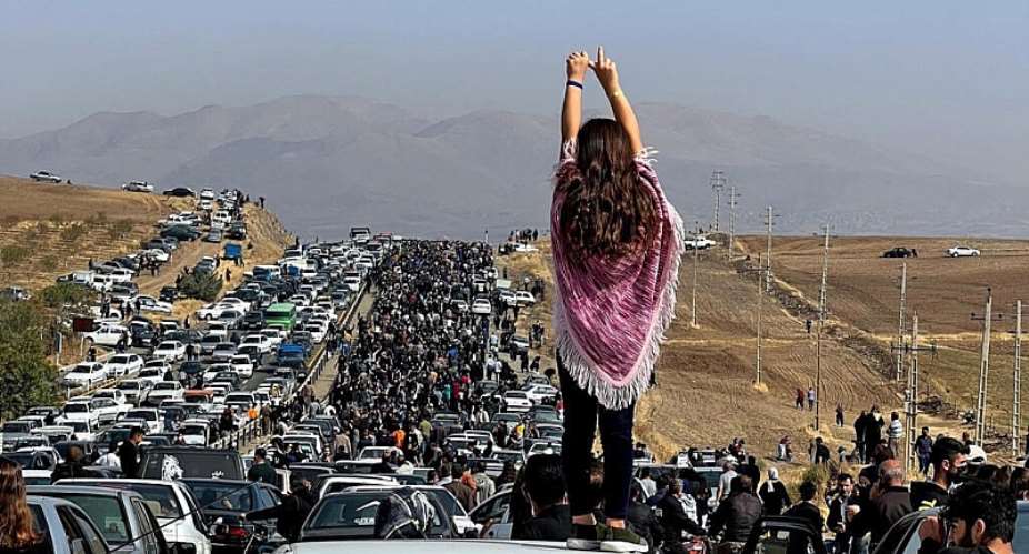 This UGC image posted on Twitter reportedly on October 26, 2022 shows an unveiled woman standing on top of a vehicle as thousands make their way towards Aichi cemetery in Saqez, Mahsa Aminis home town in the western Iranian province of Kurdistan. -  AFP, X