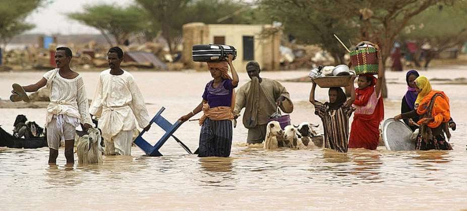 Sudanese people carry their belongings through the flood waters - Source: Isam Al-HajAFP via Getty Images