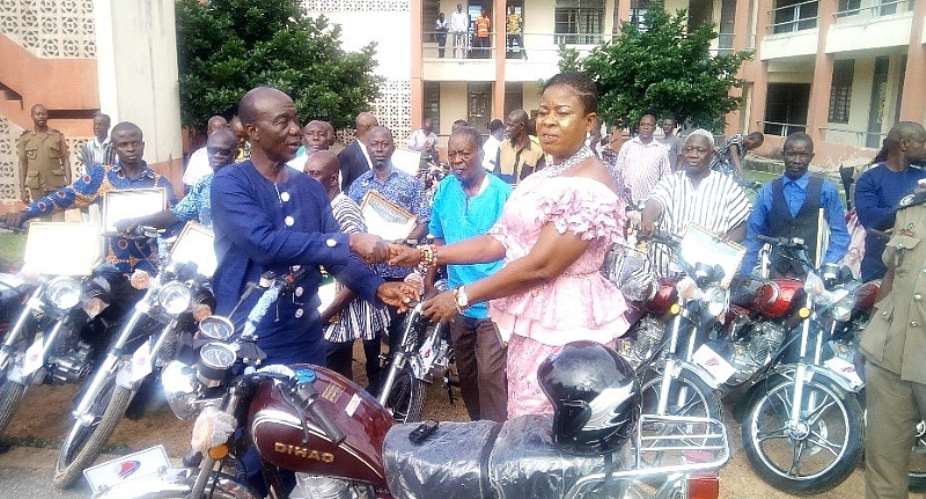 Hon. Kena handing the bikes over to the PM, Hon.Kate Mawusi