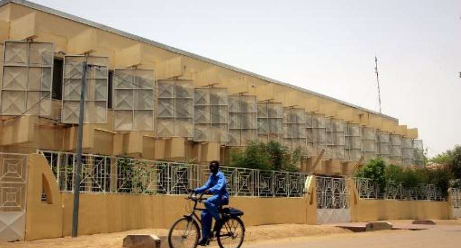 A cyclist passes in front of a high school, on May 6, 2006, in N'djamena, Chad.  By Issouf Sanogo AFPFile
