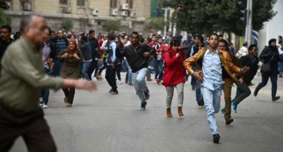 Opponents to Egyptian President Abdel Fattah al-Sisi run for cover during clashes in Cairo on January 25, 2015, marking the fourth anniversary of the 2011 uprising that ousted Hosni Mubarak.  By Mohamed El-Shahed AFP