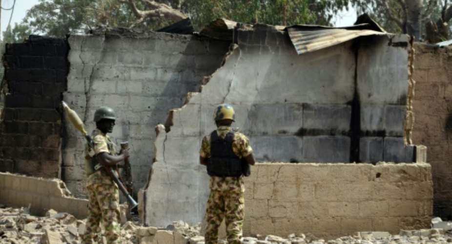 Soldiers looks at a burnt house on February 4, 2016 in the village of Dalori in northeastern Nigeria, after an attack by Boko Haram on January 30, 2016.  By  AFPFile