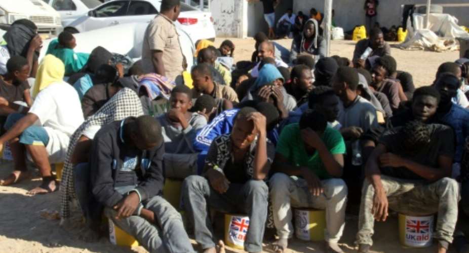 Illegal migrants sit in a port in Tagiura, east of the Libyan capital Tripoli, after 137 migrants of African origins were rescued by coast guard boats off the coast of Libya on July 21, 2016.  By STRINGER AFPFile