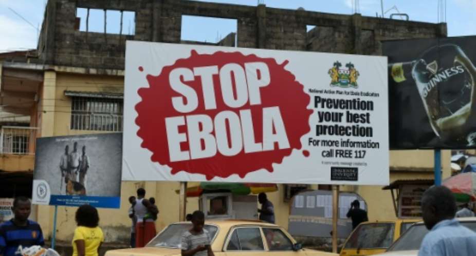 People walk past a billboard with a message about Ebola in Freetown, on November 7, 2014.  By Francisco Leong AFPFile