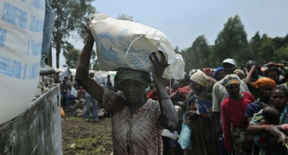 A displaced Congolese woman volunteers to offload sacks of maize-flour during a food aid distribution at a camp for the internally displaced in Mugunga, on  November 24, 2012.  By Tony Karumba AFPFile