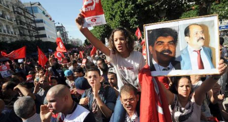Tunisian opposition activists shout slogans as they hold portraits of assassinated opposition figures Mohamed al-Brahmi (left) and Chokri Belaid during a demonstration in Tunis, on October 23, 2013.  By Fethi Belaid (AFP)