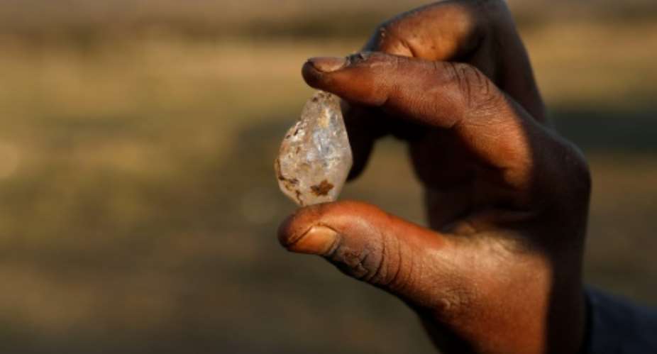 A boy holds what he believes to be a diamond dug out of the ground at KwaHlathi village near Ladysmith, South Africa.  By Phill Magakoe AFP