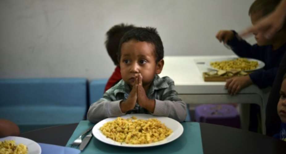 A child prays before eating at the Kapuy Foundation shelter which supports children abandoned, or with serious health problems, including undernourishment in Venezuela.  By YURI CORTEZ AFPFile