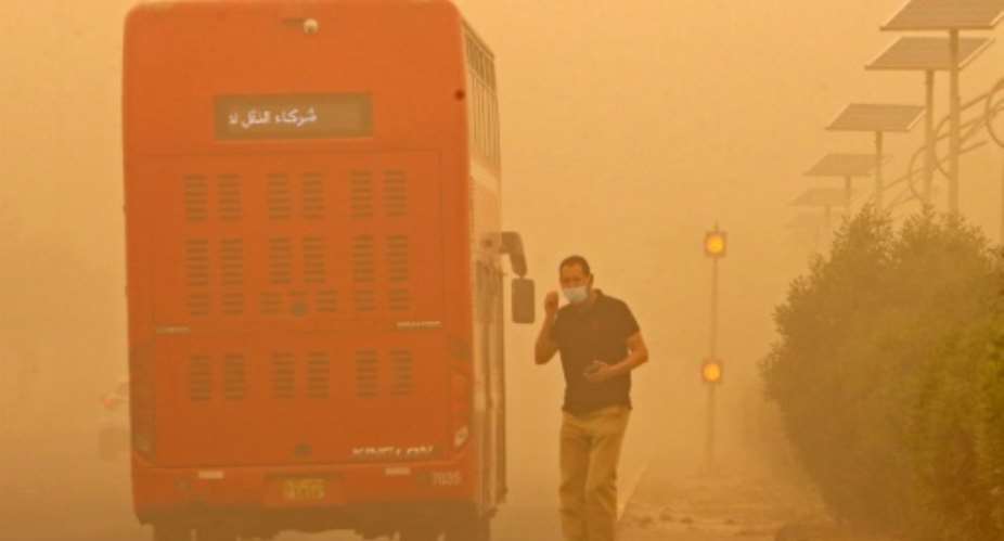 A commuter in Kuwait City waits to cross a street amid heavy sandstorms that have engulfed the Middle East.  By YASSER AL-ZAYYAT AFP