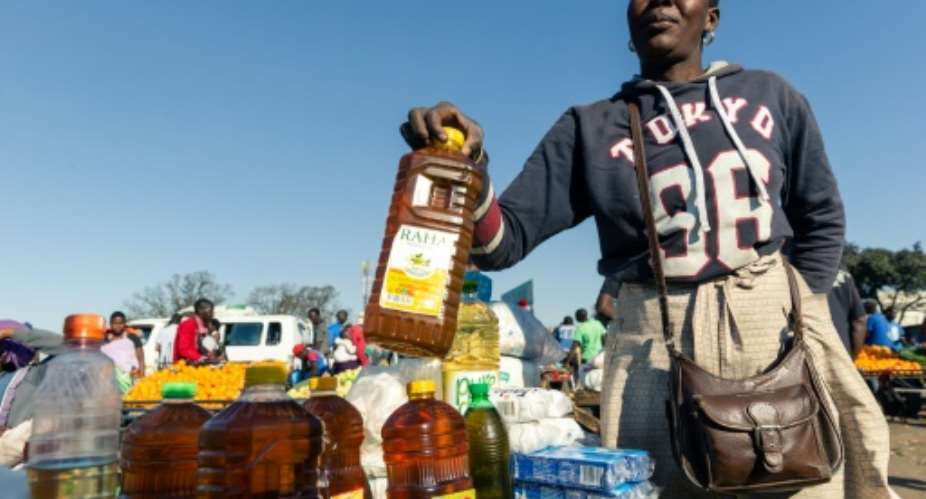 A customer buys cooking oil at a stall where smaller than standard measures of cooking oil is sold at Harare Mbare Musika marketplace as inflation sends food prices soaring.  By Jekesai NJIKIZANA AFP