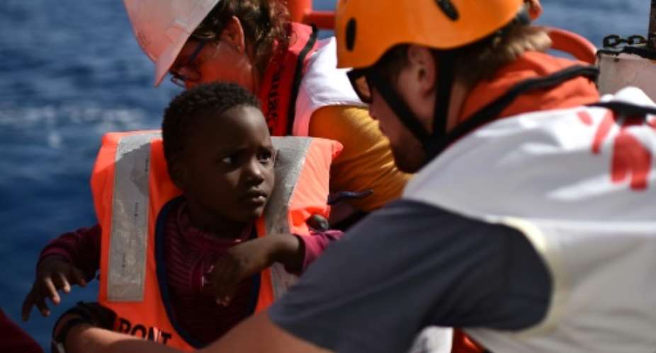 Rescuers take care of a child during a migrant rescue operationon MS Aquarius on May 24, 2016 in the Mediterranean Sea.  By Gabriel Bouys AFP