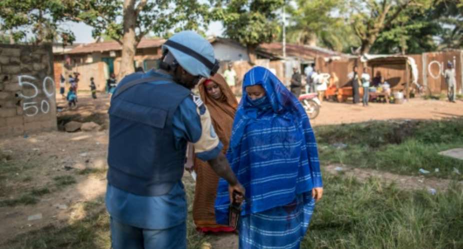 A Burundian soldier of the UN peacekeeping force MINUSCA contingent uses a metal detector at the entrance of a polling station in the flashpoint PK5 district in Bangui on December 14, 2015.  By Marco Longari (AFP)