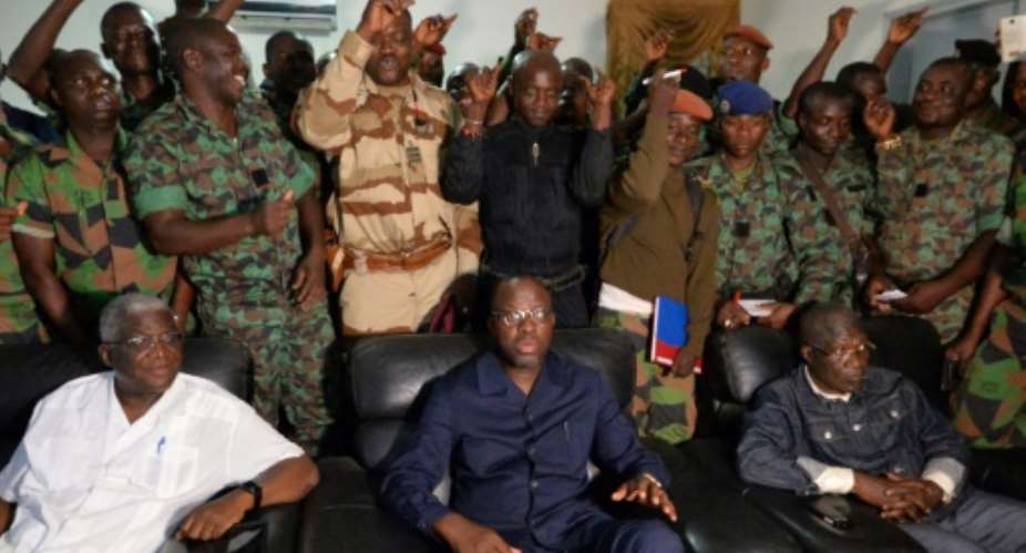 A delegation of mutinous soldiers stand behind Ivory Coast's defence minister Alain-Richard Donwahi C-front speaking to journalists after negotiations, on January 7, 2017 in Bouake.  By SIA KAMBOU AFP