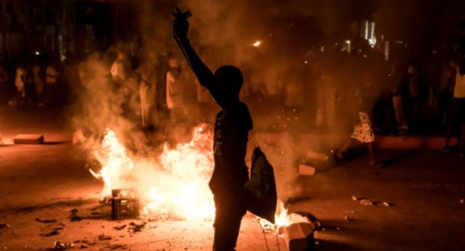 A demonstrator stands next to a burning barricade during a protest over The Gambias electricity crisis.  By Muhamadou BITTAYE (AFP)
