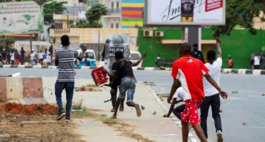 A demonstrator throws a rock at police office during the protests in Luanda on October 24.  By Osvaldo Silva AFP