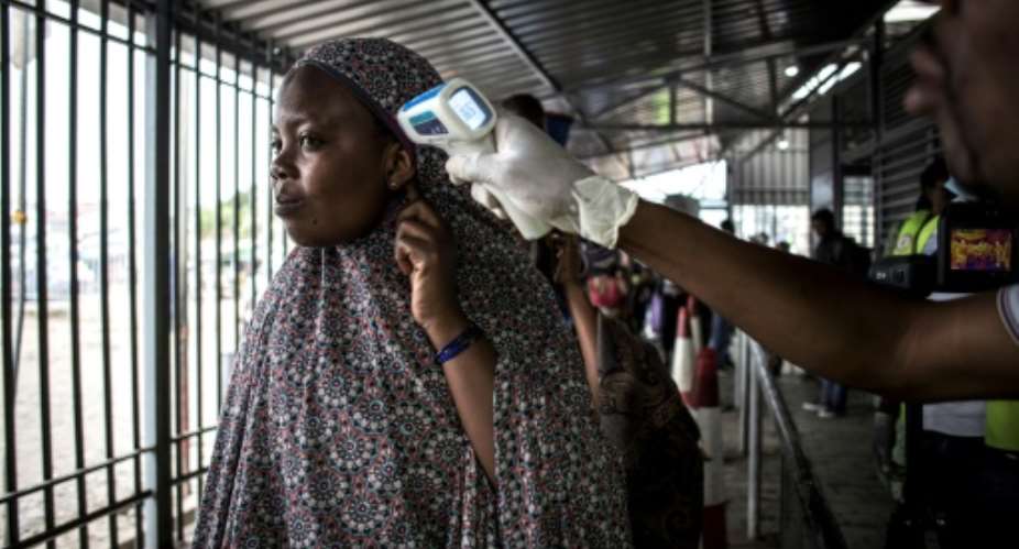 A DR Congo health worker takes the temperature of a woman on the border with Rwanda as part of efforts to contain the Ebola epidemic.  By JOHN WESSELS AFP