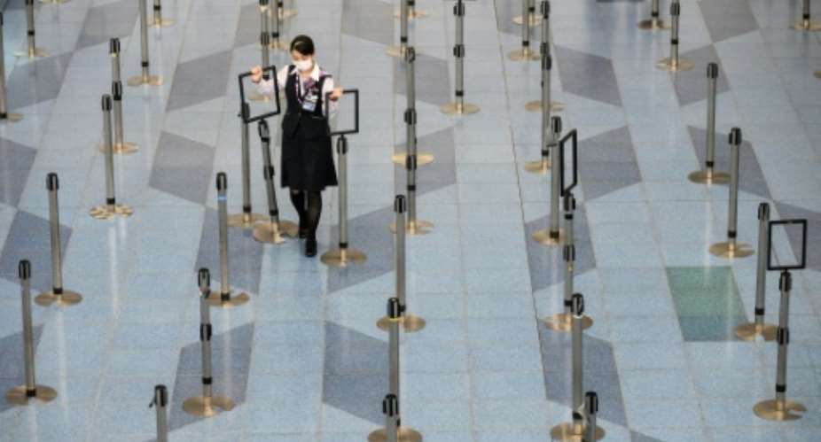 A facemask-clad airline employee works in a near empty the departure hall at Tokyo's Haneda Airport.  By Philip FONG AFP