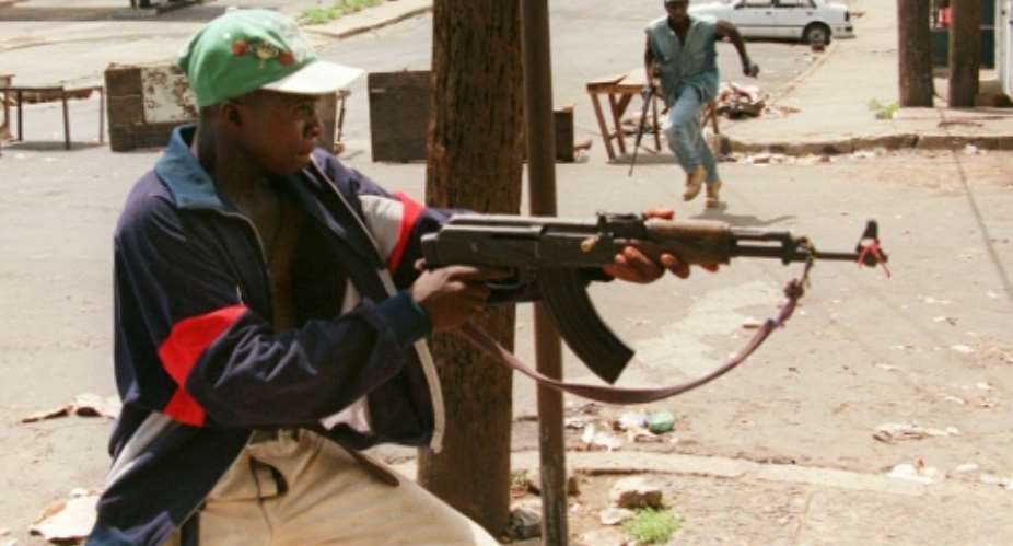 A fighter with Charles Taylor's NPFL fires at rivals from the United Liberation Movement of Liberia for Democracy ULIMO during Liberia's civil war in May 1996.  By CHRISTOPHE SIMON AFPFile