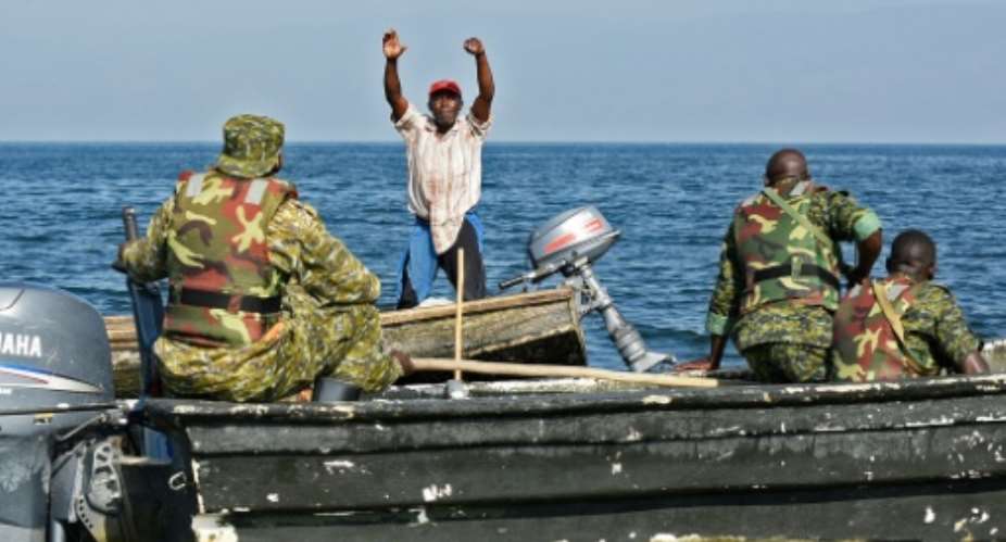 A fisherman from the Democratic Republic of Congo raises his hands  to surrender to Uganda forces patrolling Lake Edward, which is shared by the two countries.  By ISAAC KASAMANI (AFP/File)