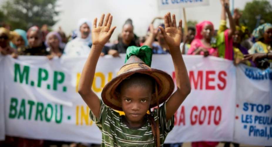 A Fulani boy protests in front of a sign saying 'Stop the Genocide' during a silent march in Bamako on June 30.  By MICHELE CATTANI AFP