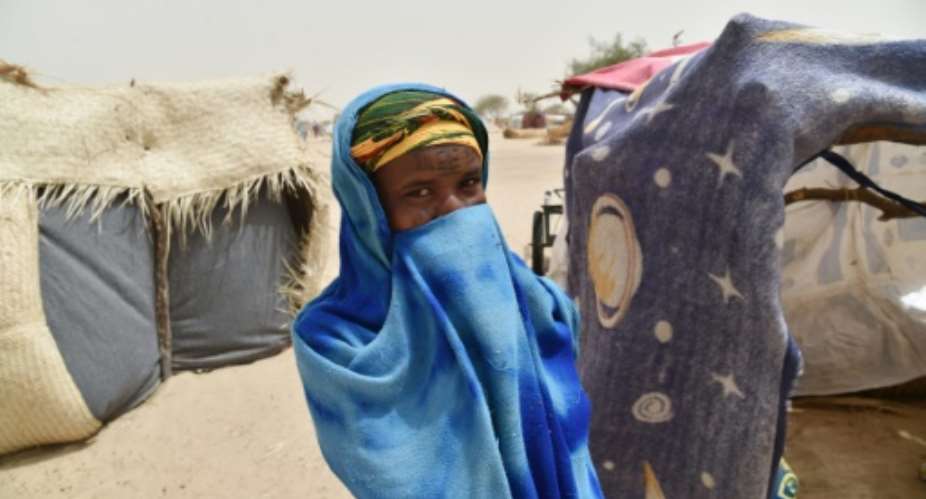 A girl hides herself next to a makeshift tent in a camp in the village of Kidjendi near Diffa, Niger on June 19, 2016 as displaced families fled from Boko Haram attacks in Bosso.  By ISSOUF SANOGO AFPFile