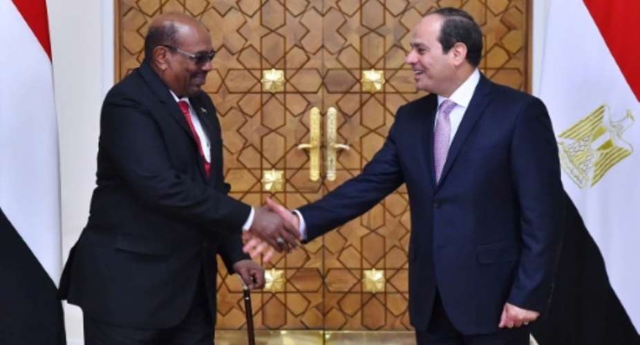 A handout picture released by the Egyptian presidency on March 19, 2018 shows Egypt's President Abdel Fattah al-Sisi L shaking hands with his Sudanese counterpart Omar al-Bashir upon his arrival at the presidential palace in Cairo.  By Handout EGYPTIAN PRESIDENCYAFP