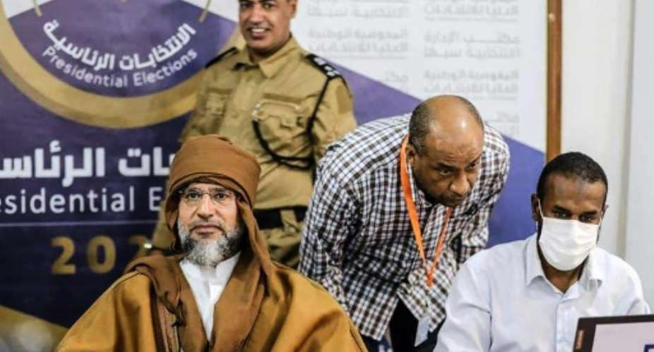 A handout picture released by the the Libyan High National Commission Facebook Page on November 14, 2021, shows Seif al-Islam Kadhafi (L) registering to run in the countrys December presidential polls, in Libyas southern city of Sebha.  By STRINGER (libyan High National Electoral Comission FB Page/AFP)