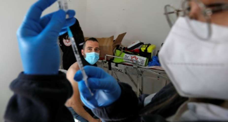 A health worker prepares a dose of the Pfizer-BioNtech vaccine on February 22, 2021 in Israel, which maintains a tight blockade on Gaza, where some 20,000 Russian-made Sputnik V vaccine doses have arrived from the United Arab Emirates.  By JALAA MAREY AFP