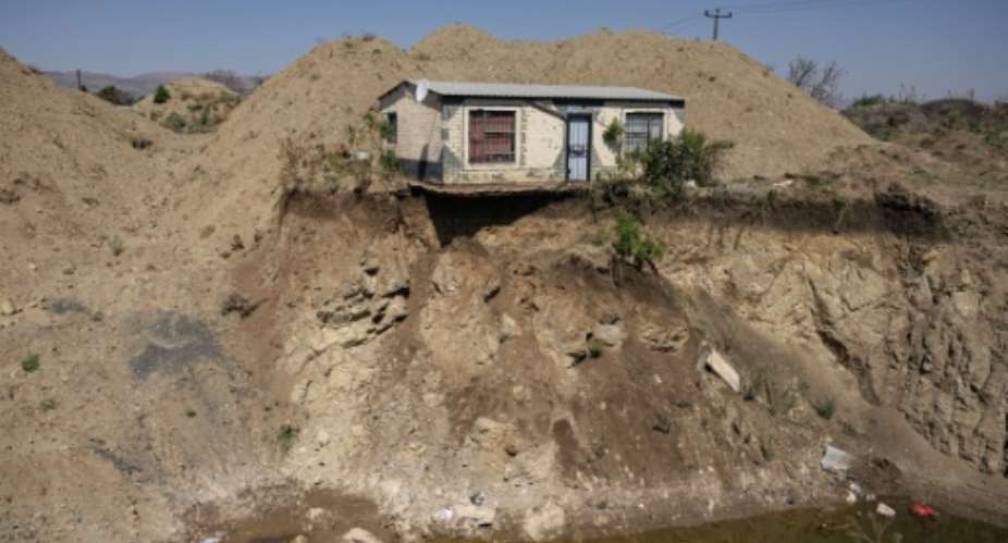 A house overlooks an open pit dug by illegal miners in Bapong, a mining village in North West province.  By EMMANUEL CROSET (AFP)