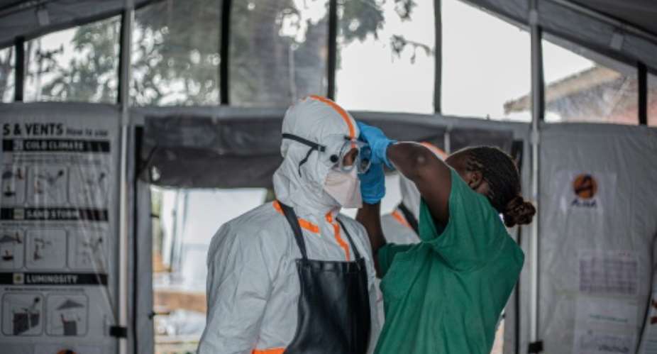 A hygiene worker helps a doctor put on personal protective equipment before entering an Ebola treatment centre in Bunia, northeastern DRC.  By BENEDICTION MURHABAZI (AFP)
