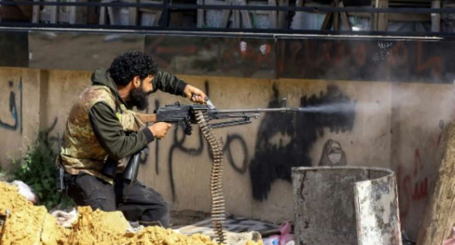 A Libyan fighter from the UN-recognised Government of National Accord fires a machinegun during clashes with forces loyal to strongman Khalifa Haftar south of the capital Tripoli's suburb of Ain Zara on April 10, 2019.  By Mahmud TURKIA AFPFile