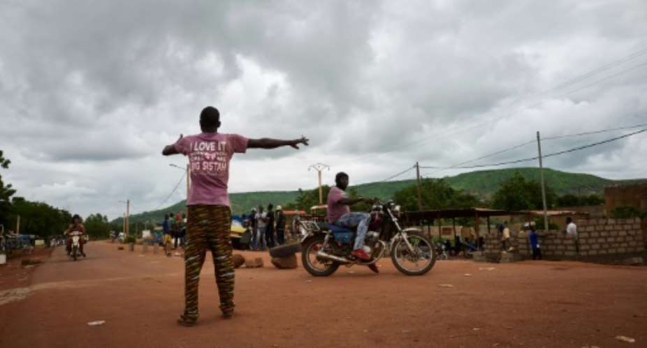 A Malian activist directs traffic on August 27, with the main road between the capital of Bamako and the western city of Kayes closed due to protest.  By MICHELE CATTANI AFPFile