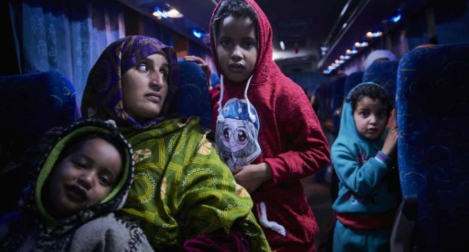 A Malian migrant woman with her children is transferred by bus to a temporary shelter upon their arrival in Bamako after being repatriated from Libya by the IOM.  By MICHELE CATTANI AFPFile