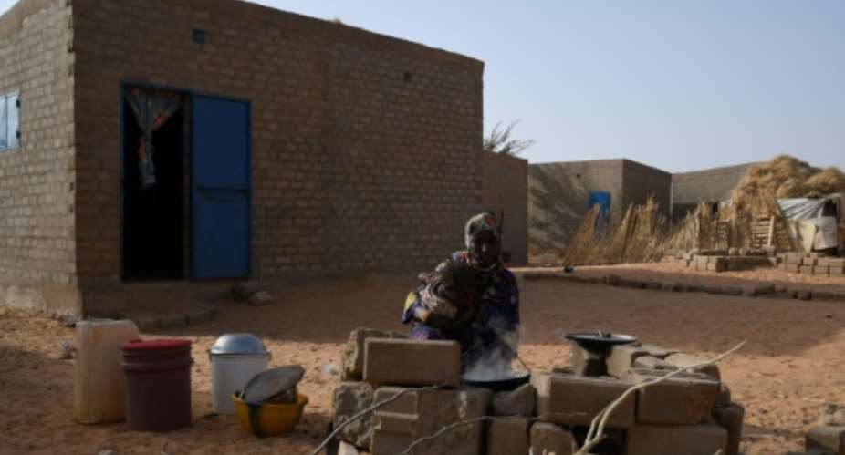 A Malian refugee cooks outside her home in Ouallam.  By BOUREIMA HAMA (AFP)