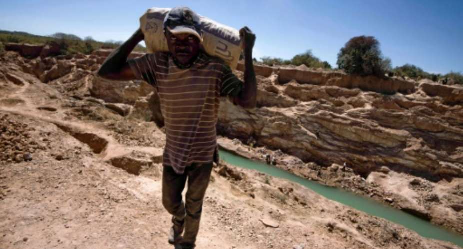 A man carries a bag at a mine for copper and cobalt in another part of DR Congo.  By JUNIOR KANNAH AFPFile