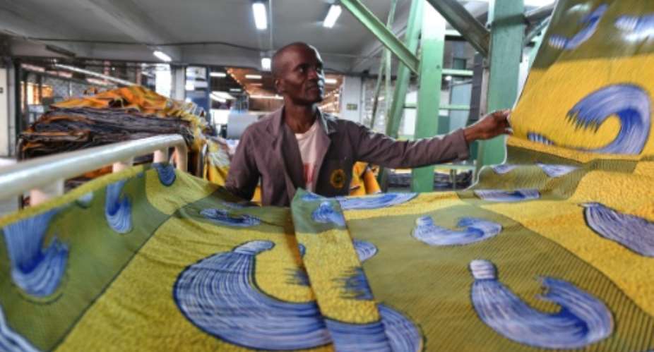 A man checks a piece of cloth in a production line at the Uniwax factory in Abidjan.  By Issouf Sanogo AFP