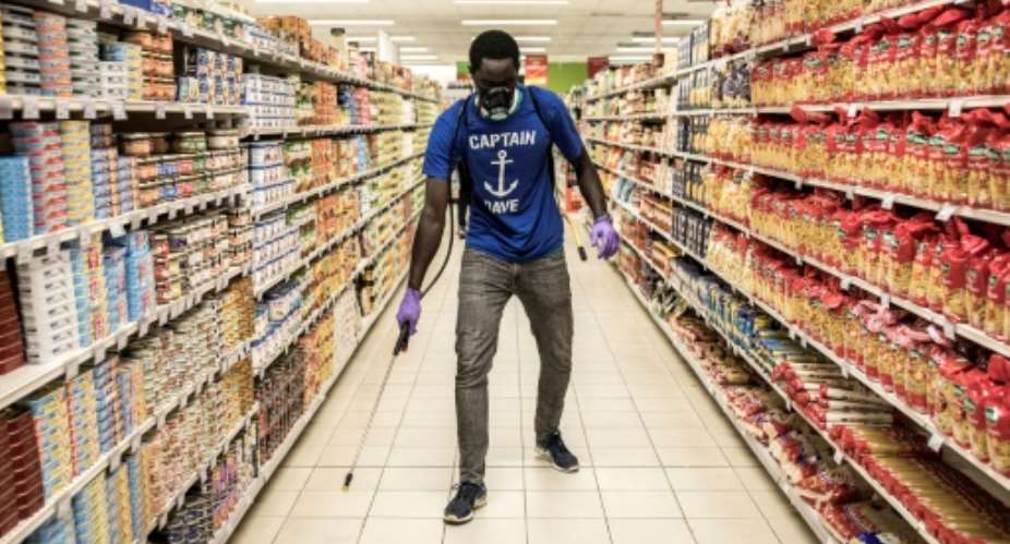 A man disinfects an empty supermarket in Dakar.  By JOHN WESSELS AFP