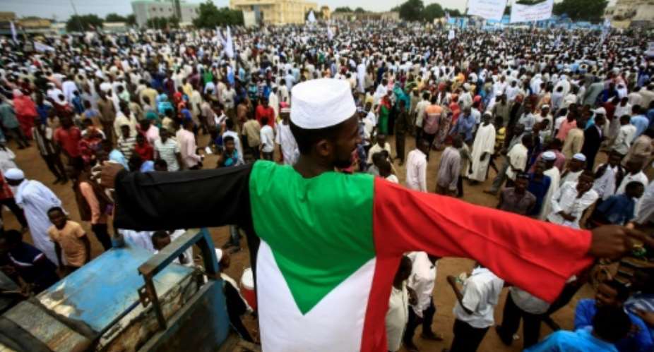A man dressed in the colours of the Sudanese national flag stands in a crowd gathered to receive President Omar al-Bashir unseen during his tour in Nyala, the capital of South Darfur province, on September 21, 2017.  By Ashraf SHAZLY AFPFile