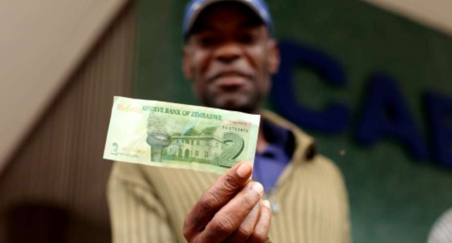 A man holds a two dollar note withdrawn from Cabs Bank in Harare on November 28, 2016.  By Wilfred Kajese AFPFile