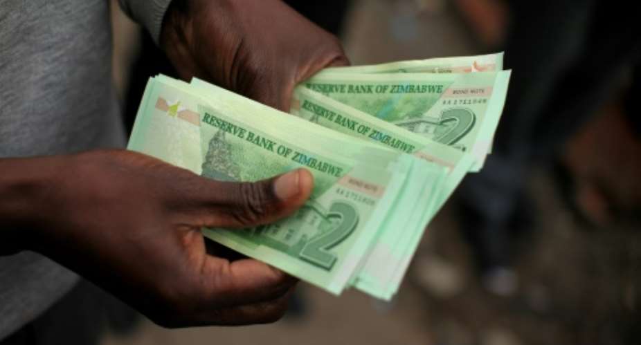 A man holds bond notes equivalent to US dollars released by the Reserve Bank of Zimbabwe to ease critical cash shortages.  By Wilfred Kajese AFPFile