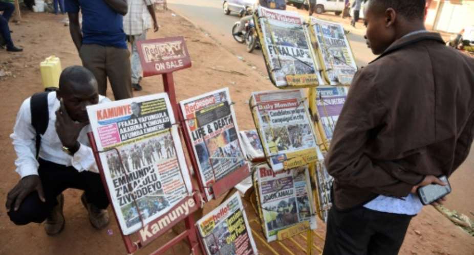 A man reads newspaper headlines at a Kampala news-stand.  By Isaac Kasamani AFPFile